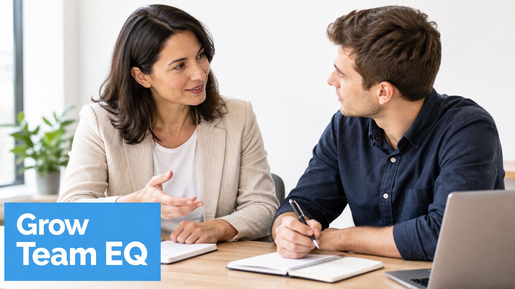 A professional woman mentoring a male colleague while they discuss work notes in a modern office setting.