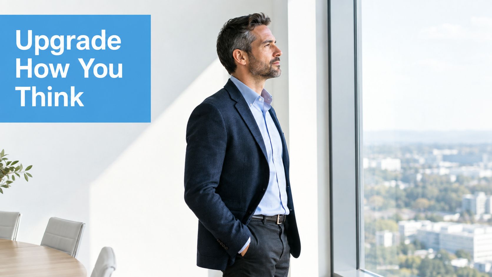 A professional man in a business suit stands in an office looking thoughtfully out a large window.