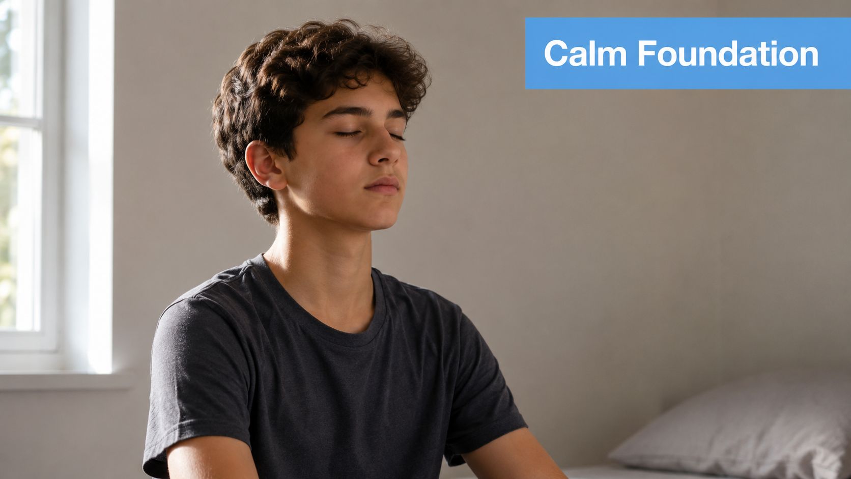A young teenager with curly brown hair meditating with eyes closed in a quiet room.